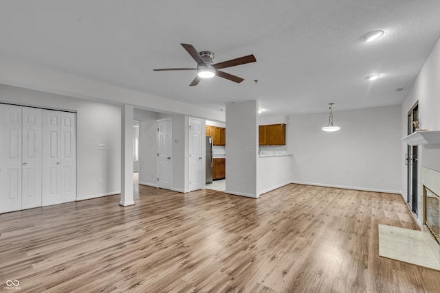 8176 Shorewalk Dr Unit C, Indianapolis, IN 46236 - unfurnished living room featuring a tiled fireplace, ceiling fan, and light wood-style floors
