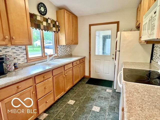1802 Laurel Dr, Columbus, IN 47203 - kitchen featuring white microwave, tasteful backsplash, light countertops, and range with electric stovetop