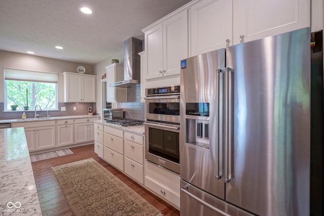 16209 Natures Way, Westfield, IN 46074 - kitchen with appliances with stainless steel finishes, wall chimney exhaust hood, light wood-style floors, white cabinets, and recessed lighting