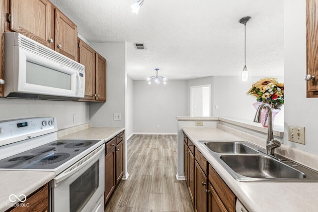 1044 Timber Creek Dr Unit 2, Carmel, IN 46032 - kitchen with white appliances, light wood-style floors, pendant lighting, brown cabinetry, and a textured ceiling
