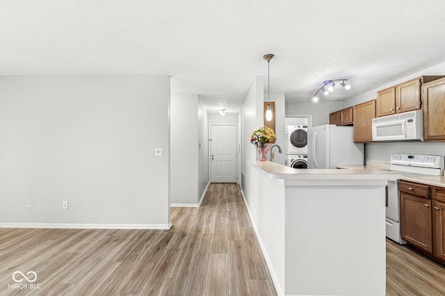 1044 Timber Creek Dr Unit 2, Carmel, IN 46032 - kitchen with white appliances, stacked washer and clothes dryer, light wood-style floors, light countertops, and a peninsula