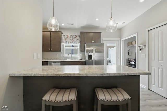 3613 Lehigh Ave, Westfield, IN 46074 - kitchen featuring appliances with stainless steel finishes, a breakfast bar, dark brown cabinets, hanging light fixtures, and recessed lighting