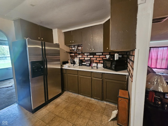 1102 S Dequincy St, Indianapolis, IN 46203 - kitchen with stainless steel fridge, black microwave, light countertops, arched walkways, and tasteful backsplash