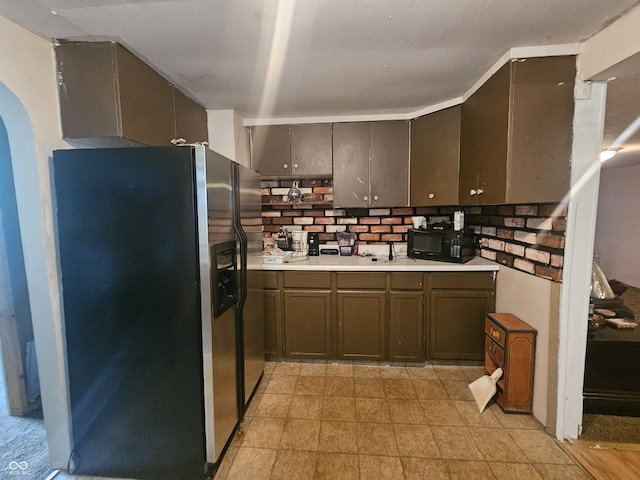 1102 S Dequincy St, Indianapolis, IN 46203 - kitchen with stainless steel fridge with ice dispenser, black microwave, arched walkways, and light countertops