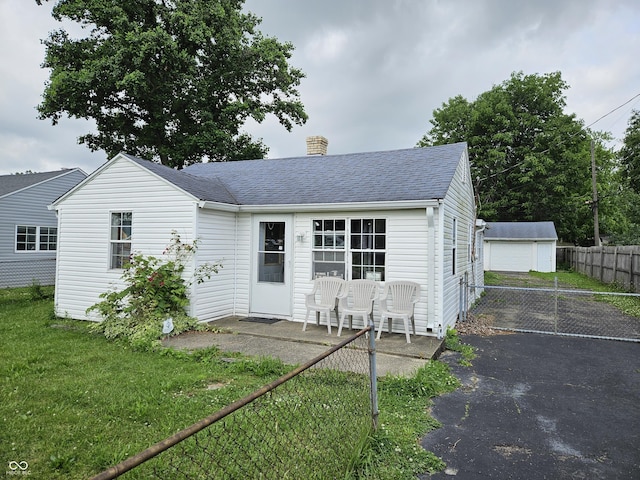 1102 S Dequincy St, Indianapolis, IN 46203 - rear view of house featuring a chimney, a shingled roof, asphalt driveway, an outdoor structure, and a detached garage