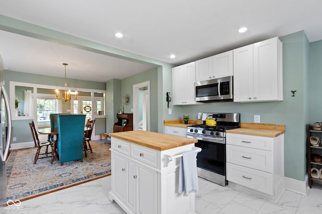 4813 E 11th St, Indianapolis, IN 46201 - kitchen with stainless steel appliances, wooden counters, light marble finish floors, a chandelier, and white cabinetry