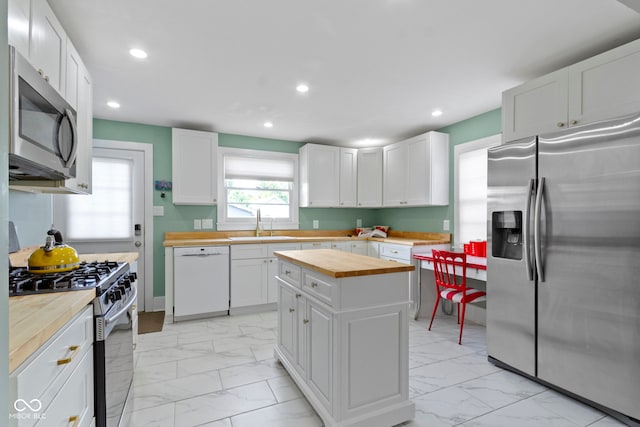 4813 E 11th St, Indianapolis, IN 46201 - kitchen featuring appliances with stainless steel finishes, butcher block countertops, light marble finish floors, a center island, and recessed lighting