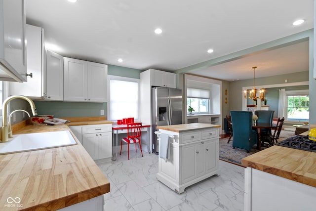4813 E 11th St, Indianapolis, IN 46201 - kitchen featuring wood counters, stainless steel refrigerator with ice dispenser, a chandelier, light marble finish flooring, and white cabinets