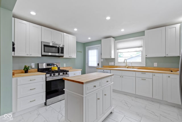4813 E 11th St, Indianapolis, IN 46201 - kitchen featuring stainless steel appliances, butcher block counters, light marble finish floors, white cabinetry, and recessed lighting