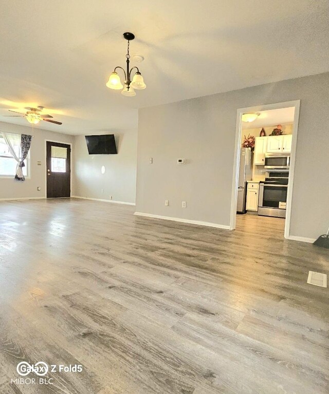 731 Sunset Blvd, Greenwood, IN 46142 - unfurnished living room featuring light wood-type flooring, baseboards, a chandelier, and ceiling fan