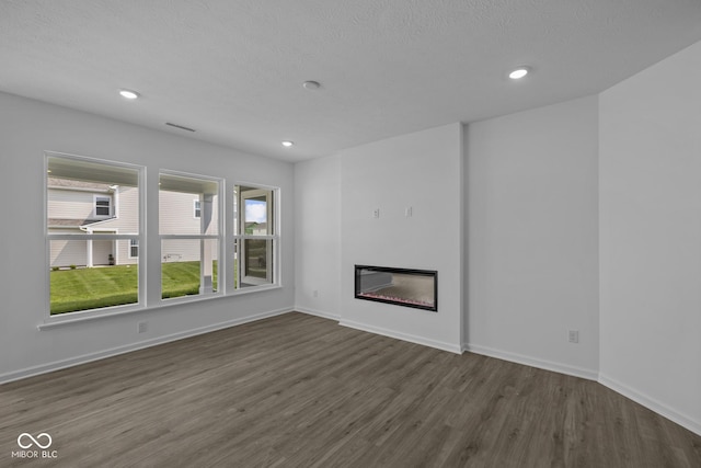 12490 Morning Ridge Way, Noblesville, IN 46060 - unfurnished living room with dark wood-style flooring, recessed lighting, a glass covered fireplace, and a textured ceiling