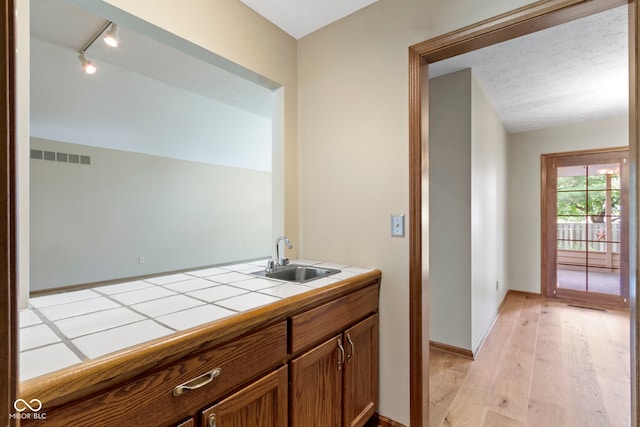 5037 Surrey Ln, Carmel, IN 46033 - kitchen with tile countertops, light wood-type flooring, rail lighting, and brown cabinetry