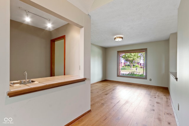 5037 Surrey Ln, Carmel, IN 46033 - spare room with rail lighting, light wood-type flooring, and a textured ceiling