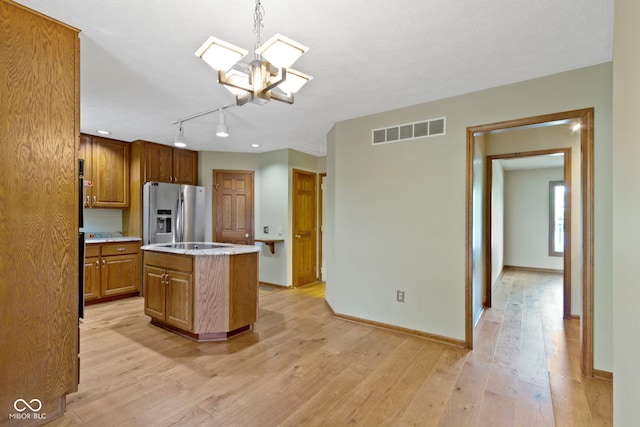 5037 Surrey Ln, Carmel, IN 46033 - kitchen with stainless steel refrigerator with ice dispenser, a kitchen island, brown cabinetry, light wood finished floors, and a chandelier