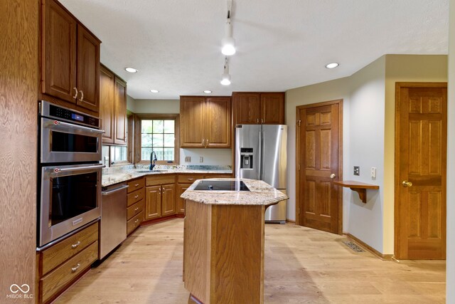 5037 Surrey Ln, Carmel, IN 46033 - kitchen with stainless steel appliances, a kitchen island, light wood-type flooring, light stone countertops, and recessed lighting
