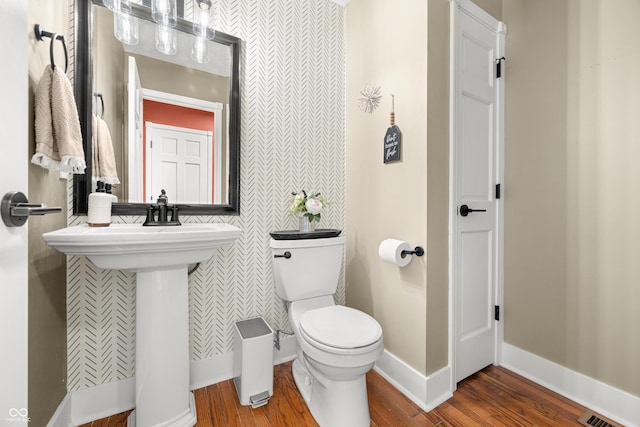 7833 Meadow Bend Dr, Indianapolis, IN 46259 - bathroom featuring wood finished floors, toilet, wallpapered walls, baseboards, and a sink