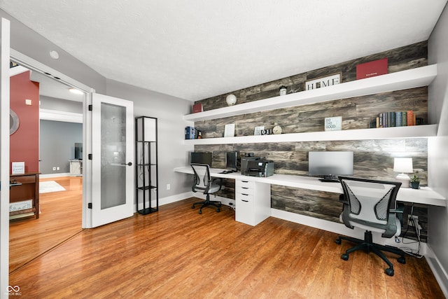 7833 Meadow Bend Dr, Indianapolis, IN 46259 - home office featuring built in desk, light wood finished floors, baseboards, french doors, and a textured ceiling
