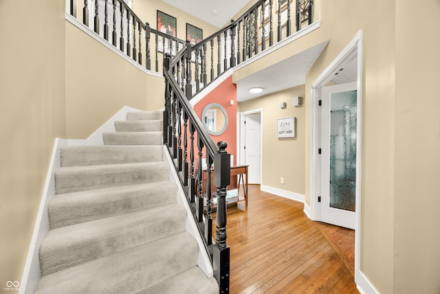 7833 Meadow Bend Dr, Indianapolis, IN 46259 - staircase featuring hardwood / wood-style flooring, baseboards, and a towering ceiling