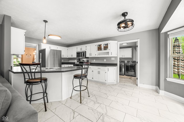 7833 Meadow Bend Dr, Indianapolis, IN 46259 - kitchen featuring appliances with stainless steel finishes, a peninsula, light marble finish flooring, washing machine and clothes dryer, and dark countertops
