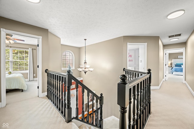 7833 Meadow Bend Dr, Indianapolis, IN 46259 - hall with an upstairs landing, light carpet, baseboards, a chandelier, and a textured ceiling