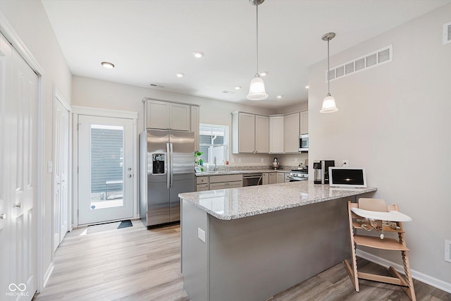 3643 Thomas Jefferson St, Westfield, IN 46074 - kitchen with stainless steel appliances, light wood-type flooring, light stone countertops, a kitchen bar, and a peninsula