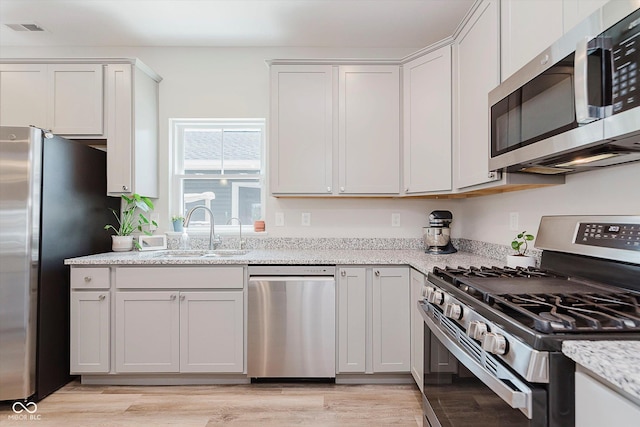 3643 Thomas Jefferson St, Westfield, IN 46074 - kitchen featuring stainless steel appliances, light wood finished floors, light stone countertops, and white cabinets