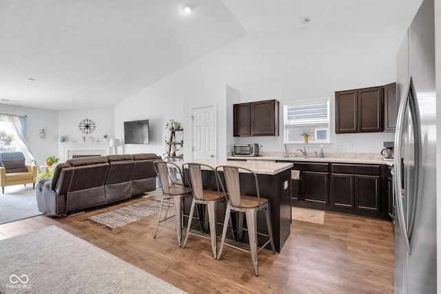 12105 Fall Ct, Indianapolis, IN 46229 - kitchen featuring freestanding refrigerator, a kitchen breakfast bar, open floor plan, dark brown cabinets, and high vaulted ceiling