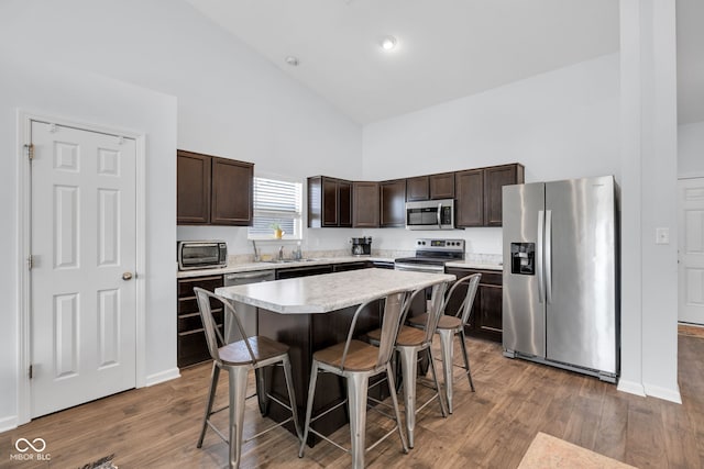 12105 Fall Ct, Indianapolis, IN 46229 - kitchen featuring stainless steel appliances, high vaulted ceiling, dark brown cabinets, a breakfast bar, and light countertops