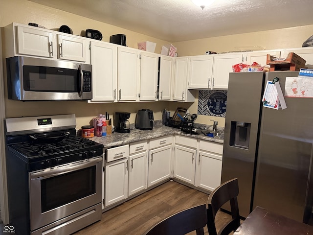 kitchen featuring appliances with stainless steel finishes, dark wood-style floors, white cabinetry, and light stone countertops