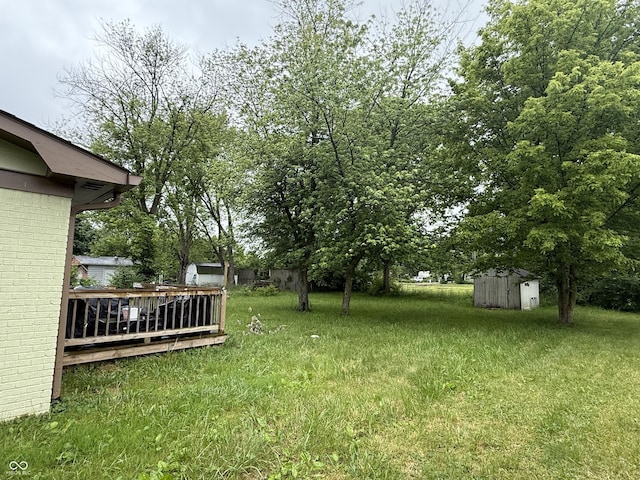 view of grassy yard featuring a storage unit and a wooden deck