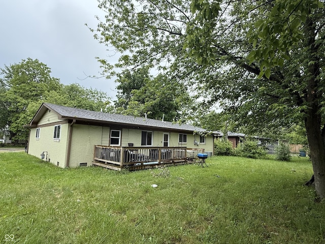 back of property with a wooden deck, brick siding, and a lawn