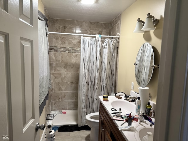full bathroom with vanity, a tile shower, and a textured ceiling
