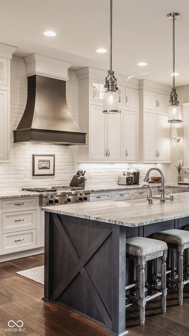 10974 Harbor Bay Dr, Fishers, IN 46040 - kitchen with premium range hood, a breakfast bar, dark wood-type flooring, white cabinets, and backsplash