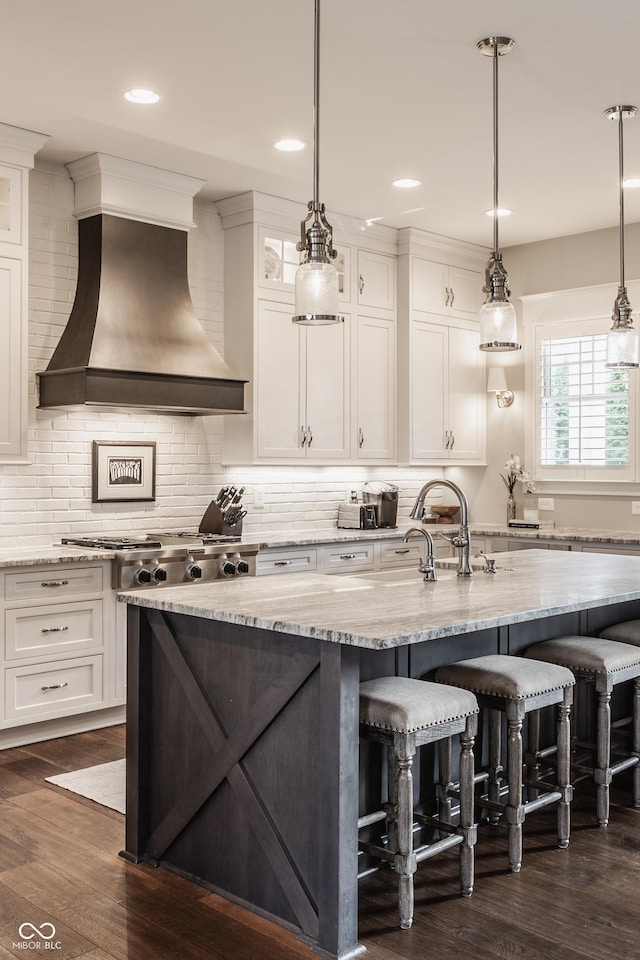 10974 Harbor Bay Dr, Fishers, IN 46040 - kitchen featuring custom range hood, a kitchen breakfast bar, dark wood-style flooring, white cabinetry, and an island with sink