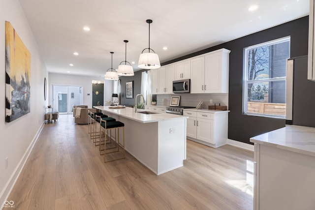 2051-2053 Columbia Ave, Indianapolis, IN 46202 - kitchen featuring appliances with stainless steel finishes, a sink, light wood-type flooring, white cabinets, and recessed lighting