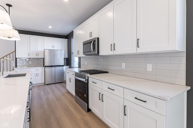 2051-2053 Columbia Ave, Indianapolis, IN 46202 - kitchen with appliances with stainless steel finishes, a sink, light wood-type flooring, recessed lighting, and tasteful backsplash