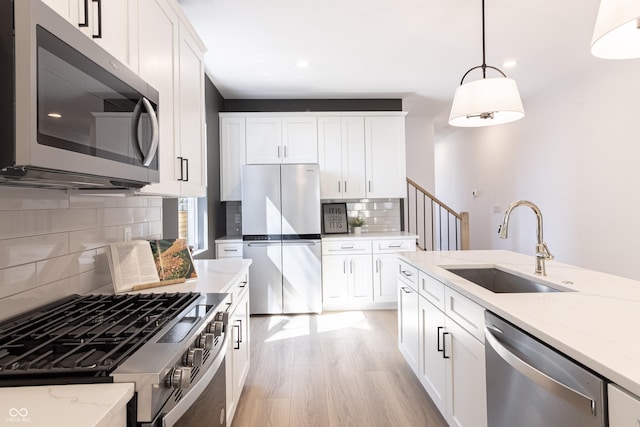 2051-2053 Columbia Ave, Indianapolis, IN 46202 - kitchen featuring appliances with stainless steel finishes, a sink, light wood-style floors, decorative backsplash, and pendant lighting