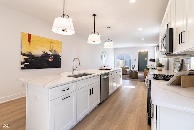 2051-2053 Columbia Ave, Indianapolis, IN 46202 - kitchen featuring appliances with stainless steel finishes, a sink, white cabinetry, light wood finished floors, and a kitchen island with sink