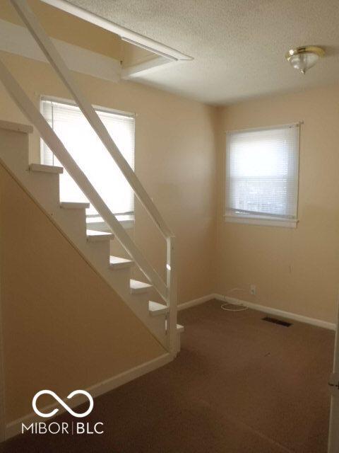 2250 N Goodlet Ave, Indianapolis, IN 46222 - stairway with a textured ceiling and carpet flooring
