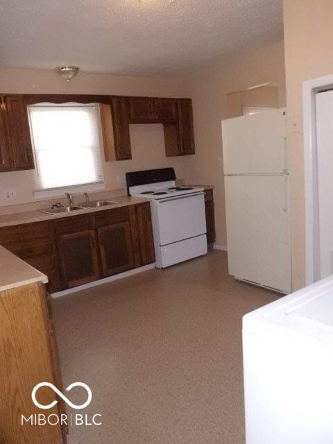 2250 N Goodlet Ave, Indianapolis, IN 46222 - kitchen with white appliances, light countertops, a textured ceiling, and washer / clothes dryer