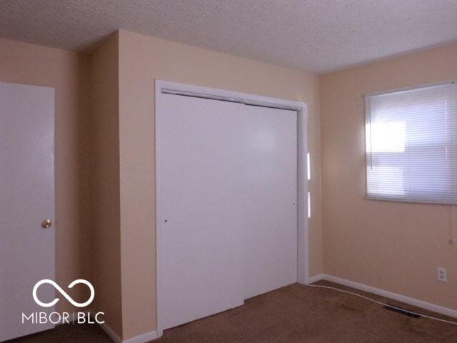 2250 N Goodlet Ave, Indianapolis, IN 46222 - unfurnished bedroom featuring carpet, a textured ceiling, and a closet