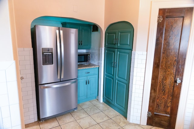 972 N Audubon Rd, Indianapolis, IN 46219 - kitchen featuring appliances with stainless steel finishes, light tile patterned floors, arched walkways, light stone countertops, and tile walls