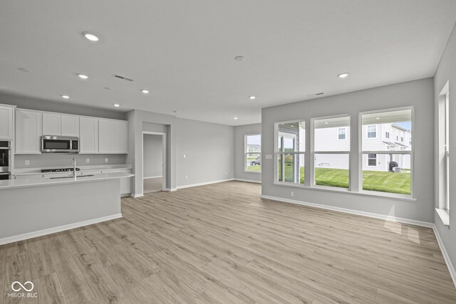 12500 Morning Ridge Way, Noblesville, IN 46060 - kitchen featuring stainless steel microwave, light countertops, recessed lighting, white cabinets, and light wood-style floors