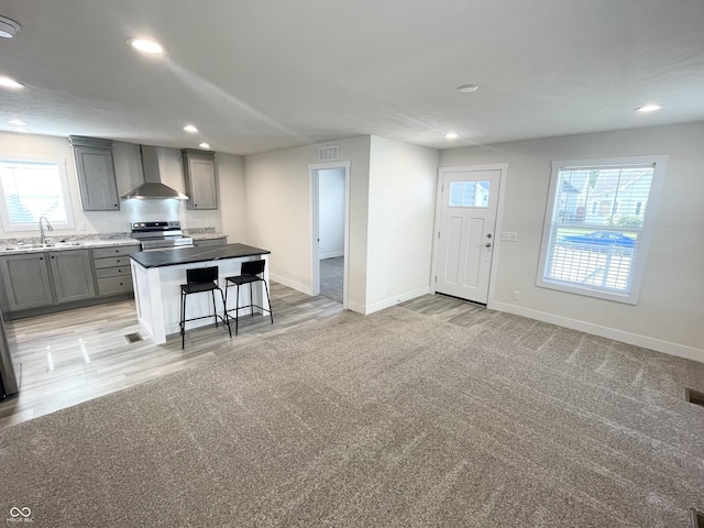 1628 Spann Ave, Indianapolis, IN 46203 - kitchen with wall chimney range hood, electric stove, gray cabinets, a kitchen island, and a breakfast bar