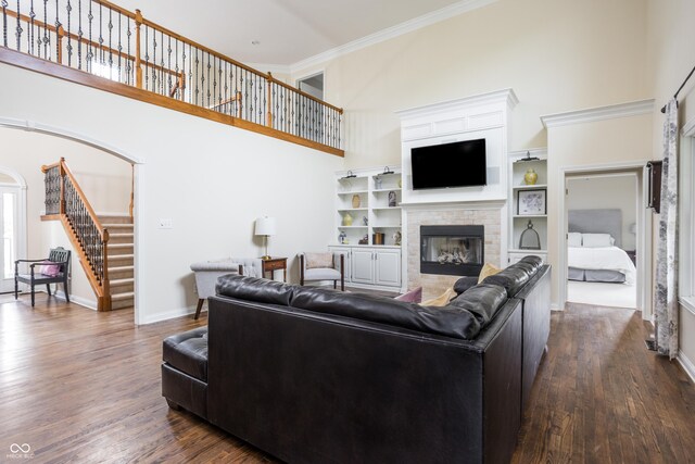 47 Torrey Pine Dr, Brownsburg, IN 46112 - living room featuring stairs, a towering ceiling, dark wood-style flooring, crown molding, and a glass covered fireplace