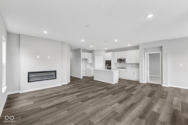 12516 Morning Ridge Way, Noblesville, IN 46060 - unfurnished living room featuring recessed lighting, dark wood-type flooring, and a glass covered fireplace
