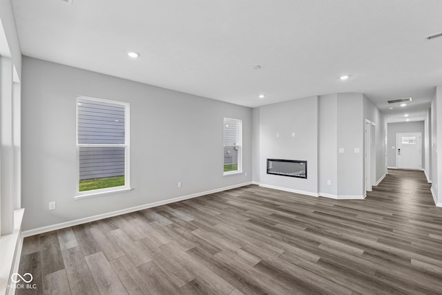 12516 Morning Ridge Way, Noblesville, IN 46060 - unfurnished living room featuring dark wood-type flooring, recessed lighting, and a glass covered fireplace