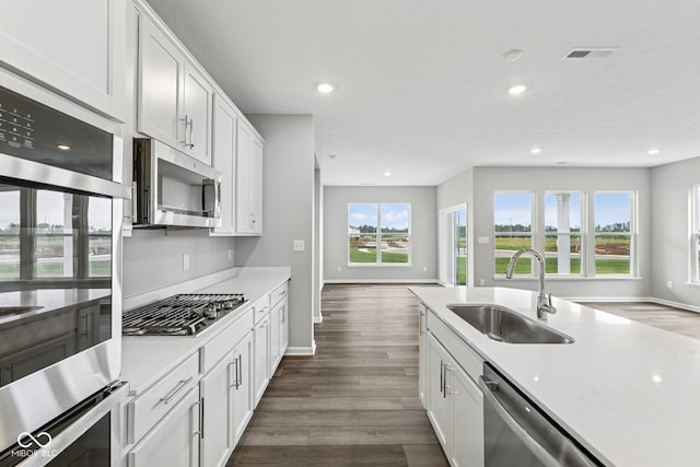 12516 Morning Ridge Way, Noblesville, IN 46060 - kitchen with stainless steel appliances, dark wood finished floors, white cabinetry, recessed lighting, and light countertops