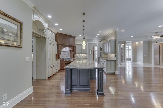 3795 Claybrook Ct, Bargersville, IN 46106 - kitchen featuring ornamental molding, a ceiling fan, tasteful backsplash, a kitchen island with sink, and stainless steel gas cooktop