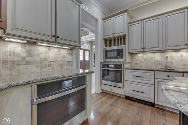 3795 Claybrook Ct, Bargersville, IN 46106 - kitchen featuring stainless steel appliances, crown molding, light stone counters, light wood finished floors, and backsplash